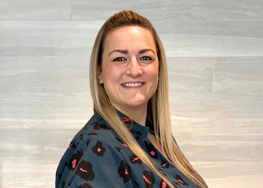 Headshot of Elisabeth Fink, employee at Fraser Stryker, wearing a dark blue shirt with black and pink dots